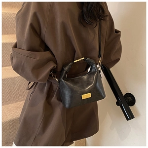 Detail of vintage matte leather handbag with gold metal handle and logo plate