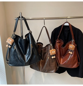 Detailed view of large tote bags in black and brown leather with cute bear charms