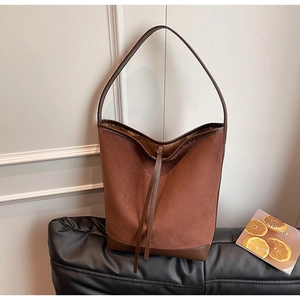 Detail of a brown suede hobo bag with leather trimming and minimalist decorative lace