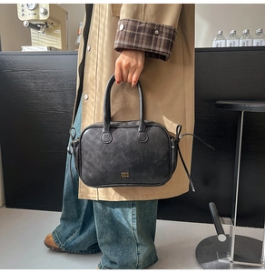 Detail of vintage black Boston bag with gold logo and side drawstring on cafe bar counter