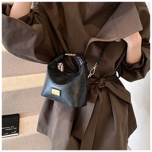 Detail of vintage black litchi pattern leather handbag with gold metal hardware on model