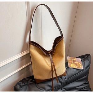 Detail of ginger suede hobo bag with dark brown leather trim and long decorative strap