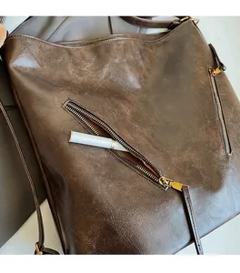 Detail of soft vintage brown leather texture and functional metal zipper on a tote bag