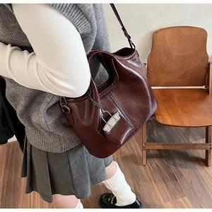 Dettaglio della borsa tote in pelle marrone rossiccio scuro con mini pochette e tracolla