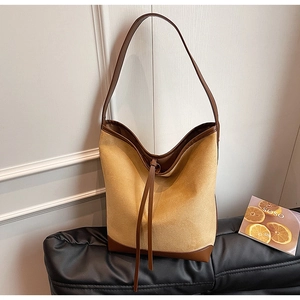 Detail of suede bucket bag with leather patchwork and drawstring in vintage style
