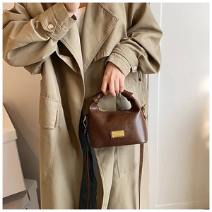 Detail of deep brown vintage crossbody bag with knotted handle and golden plaque