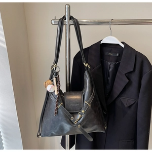Detalle del bolso tote gris con amuleto de béisbol, hebilla de metal y cuero grabado