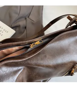 Close-up of smooth gold-tone zipper on dark brown vintage PU leather tote bag