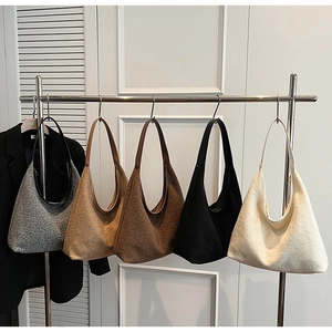 Five wool felt hobo bags in assorted colors hanging on a minimal white wall