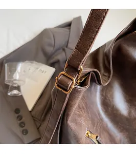 Close-up of vintage brown leather texture and golden metal buckle on a retro tote bag