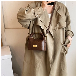 Detail of vintage brown textured leather handbag with gold metal handle and shoulder strap
