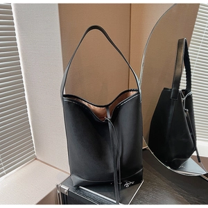 Detail of black suede tote bag with leather piping reflected in a round mirror
