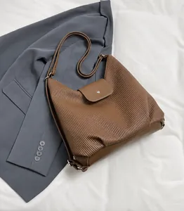 Detalle de bolso bandolera vintage marrón con textura plisada vertical y cierre de hebilla metálica