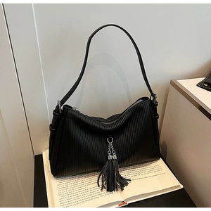 Detail of black pleated leather crescent bag with silver fringe on vintage book