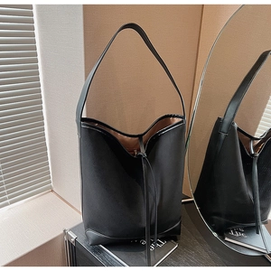 Detail of black large suede shoulder bucket bag with drawstring and leather trim accents