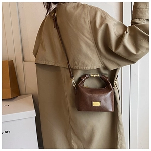 Detail view of a vintage dark brown leather handbag styled with an autumn trench coat