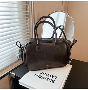 Detailed shot of dark brown vintage leather handbag with gold hardware and side pleats