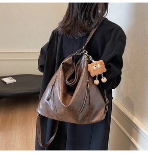 Detail view of large dark brown retro PU leather backpack with vintage texture and charms