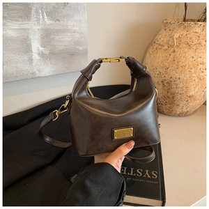 Detail of vintage brown leather handbag with gold buckle on a black blazer jacket