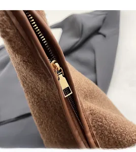 Close-up of a smooth gold metal zipper on a premium brown wool tote bag texture