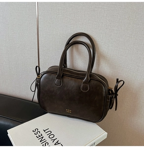 Detail view of a vintage dark brown handbag featuring side bow drawstring accents