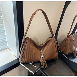 Detail of brown pleated leather bag with double tassel metal pendants and shoulder strap