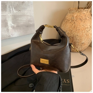 Detail of vintage brown crescent handbag with gold clasp and textured leather surface