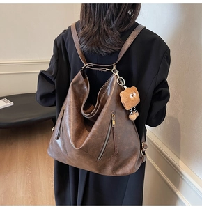 Detail view of vintage brown soft leather backpack with twin zippers and plush charm