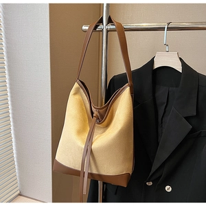 Detail of the contrast stitching and premium brown leather trim on a hobo bucket bag