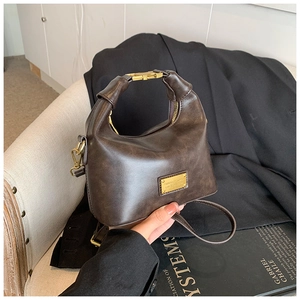 Detailed close-up of dark brown crescent bag with gold-tone hardware and vintage texture