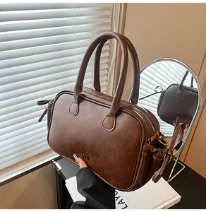 Detailed view of deep brown vintage handbag featuring metal logo and smooth leather texture