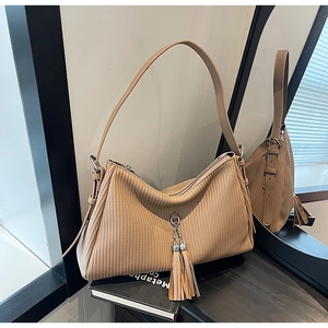 Detailed close-up of khaki pleated leather shoulder bag with metallic tassel charms