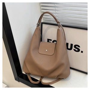 Detalle de mochila de cuero marrón tierra con pliegues verticales y hebilla de plata