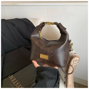 Detail of vintage brown leather handbag with metallic buckle handle and gold logo plate