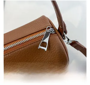 Close-up of caramel brown pebble leather texture and smooth silver metal zipper on the bag