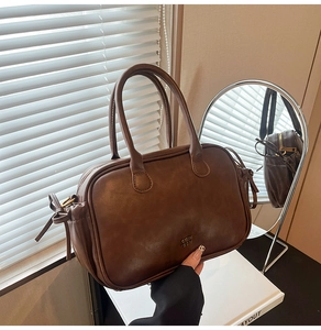 Detail of vintage dark brown handbag with COIH 2DN text and stylish bow drawstring detail