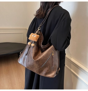 Detail view of brown large capacity tote bag in vintage oil wax leather with bear charm
