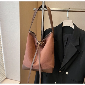 Detail of vintage brown suede bucket bag with leather stitching on a garment rack
