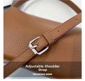 Detail of adjustable leather shoulder strap with silver buckle on brown pillow bag