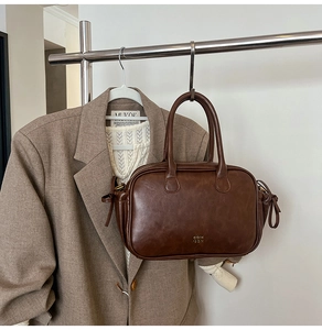 Detailed close-up of dark brown vintage leather handbag hanging against a matching suit jacket