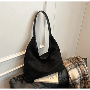 Detail of black textured fuzzy hobo bag on leather seat with autumn accessories