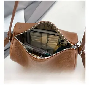 Overhead shot of brown cylinder bag interior showing phone, wallet and cosmetics
