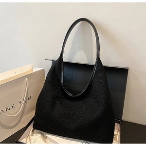 Detailed view of black textured fleece tote bag with glossy leather handles in a gift box