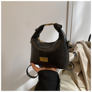 Close-up of black leather handbag featuring a half-moon shape with gold metal buckle detail