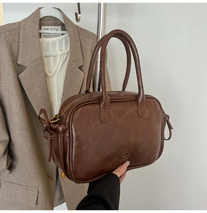 Close-up of vintage brown leather handbag with gold logo and side bow detail