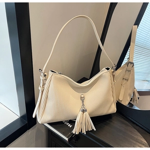 Detailed macro view of cream corduroy shoulder bag featuring leather tassels and texture