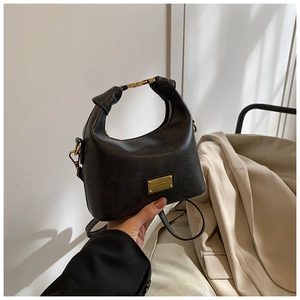 Detail of a vintage black hobo bag with a gold metal plaque and high-quality leather texture