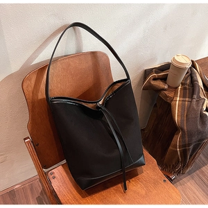 Detail of canvas and black leather bucket bag on a vintage chair in a cafe setting