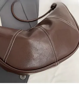 Macro detail of the dark brown croissant bag showing stitching on leather texture