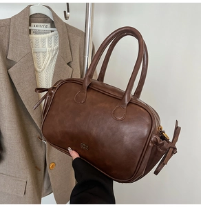 Detail of vintage dark brown faux leather mini Boston bag with bow and gold logo